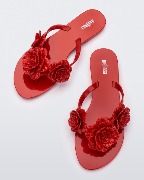 Top view of a pair of red Harmonic Springtime women's flip flop with 3 red flowers.