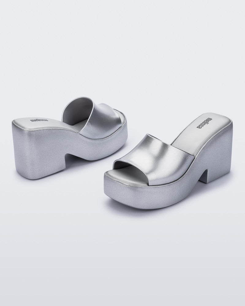 Angled shot of a pair of Melissa Posh platform slides in Silver