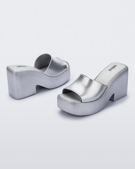 Angled shot of a pair of Melissa Posh platform slides in Silver