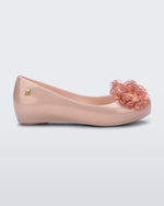 Side view of a pearly pink Ultragirl Springtime kids flat with two clear pink flowers and peep toe.