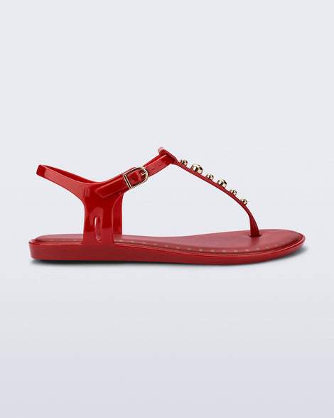 Side view of a red Solar Boho t-strap sandal with ,metallic detailing on the front strap