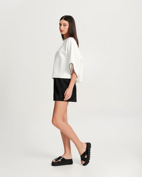 Model in a black skirt and white shirt wearing a pair of black Cozy Cross platform sandals with crisscross top straps