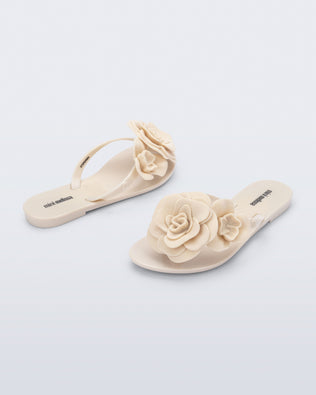 Back and angled view of a pair of beige Harmonic Petals kids flip flops with flowers