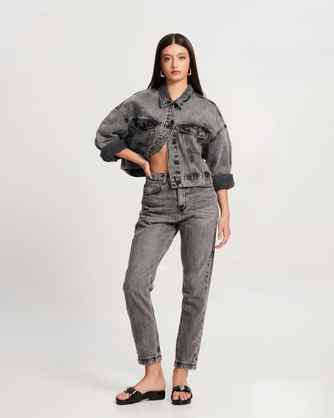 Model in black jean pants and jacket wearing a pair of black Pescura Heel + Scholl slides with top buckle