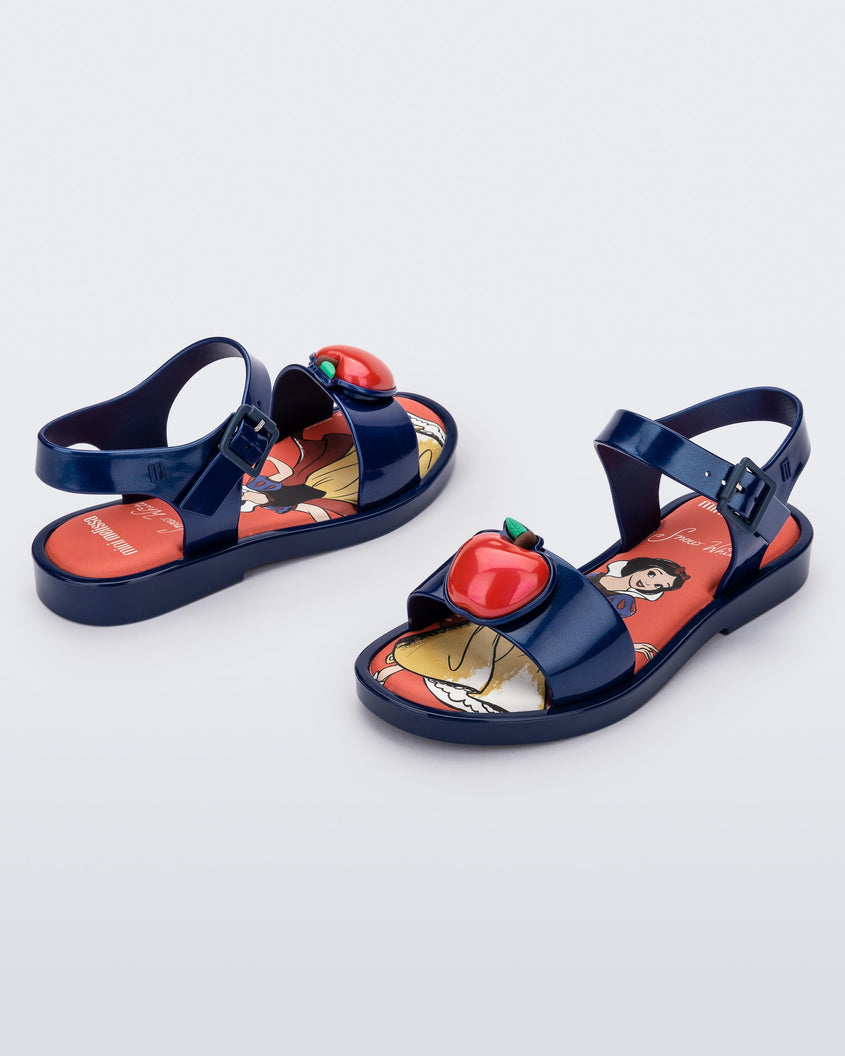 An angled front and side view of a pair of metallic blue Mini Melissa Mar Sandal Princess sandals with an apple detail on the front strap, an ankle strap and Princess Snow White soul