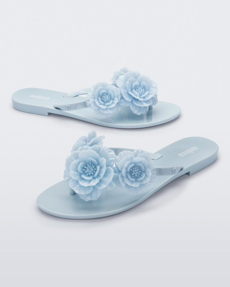 Angled view of a pair of blue Harmonic Springtime women's flip flop with 3 blue flowers.