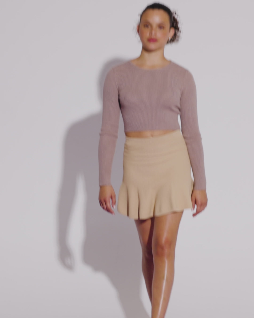 Video with no sound of a model in a beige shirt and skirt wearing a pair of light beige Doll flats.