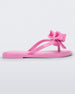 Side view of a pink Mini Melissa Slim flip flop with a lace like bow detail on the front strap.