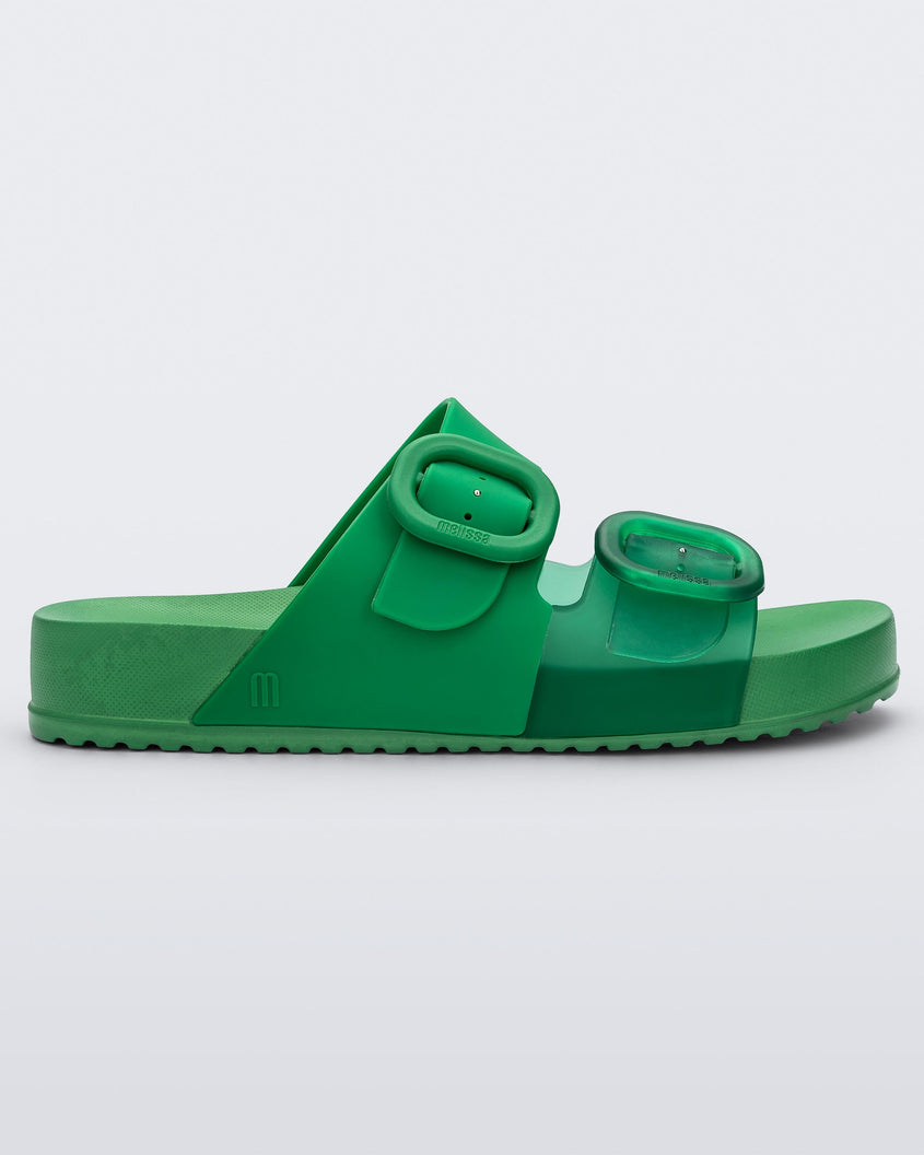 Side view of a Green Melissa Cozy slide with two green and transparent green straps with a buckle detail.