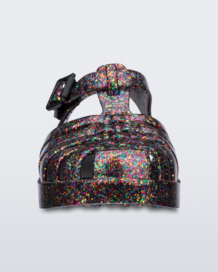 Front view of a Mixed Glitter Glass Mini Melissa Possession sandal with multiple multicolor glitter straps, black buckle and a multicolor glitter sole.