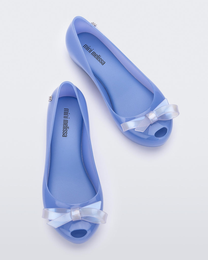 Top view of a pair of blue Mini Melissa Ultragirl Bow flats with a blue base and a white bow.