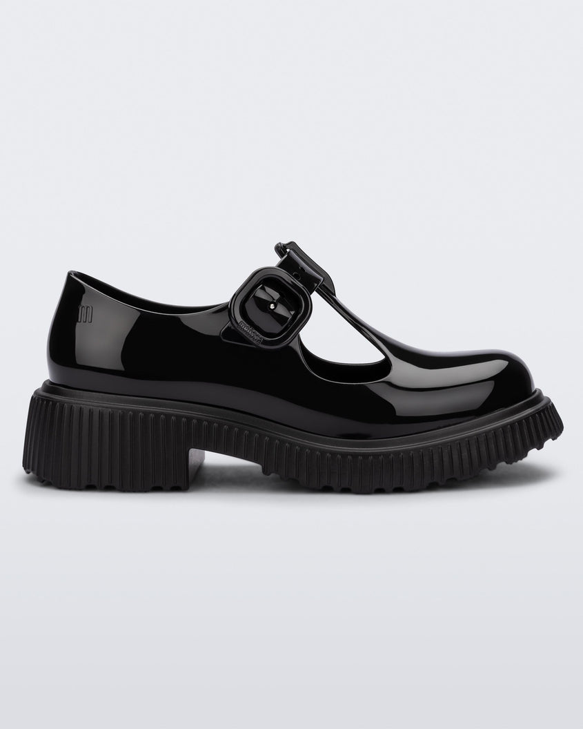 Side view of a black Mini Melissa Jackie loafer with two cut outs and a buckle detail strap.