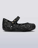 An outter side view of a Black/Silver Glitter Mini Melissa Campana Zig Zag flat with a top strap and a woven detail design.