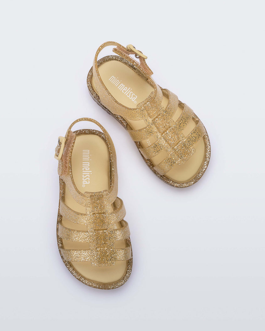 A top view of a pair of clear yellow glitter Mini Melissa Flox sandals with straps.