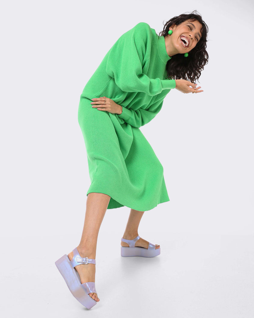 A model posing for a picture with her arms crossed in a green dress and a pair of pearly blue Melissa Mar Platform sandals with two straps.