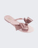 An angled side view of a light pink Mini Melissa Harmonic Bow flip flop with a light pink base and a glitter pink bow.