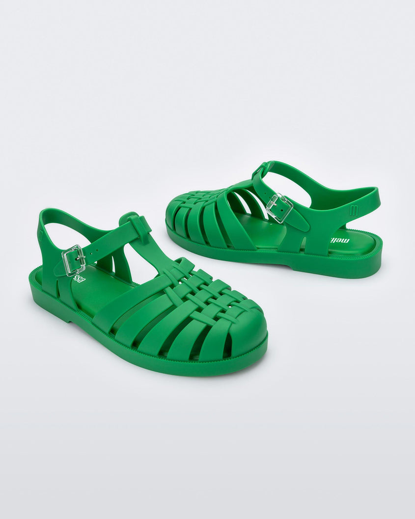 Angled view of a pair of green Melissa Possession sandals with a closed toe front weft design connected to a top strap with a buckle.