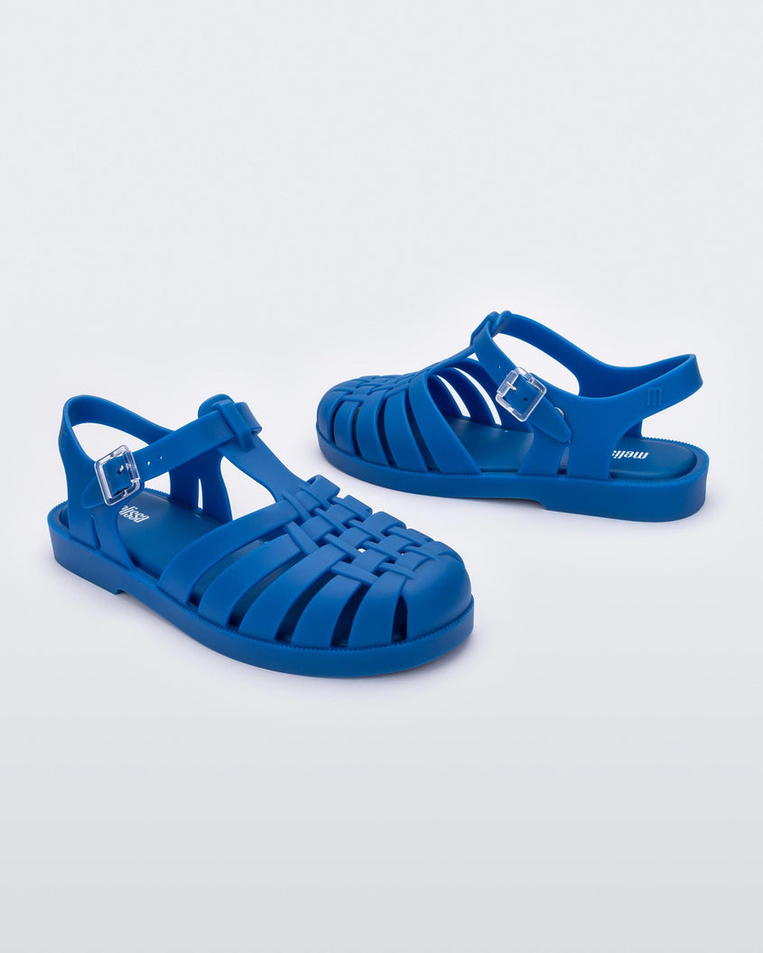 Angled view of a pair of Melissa Possession fisherman sandals in blue, with cut out fishermen strap detail and clear buckle closure