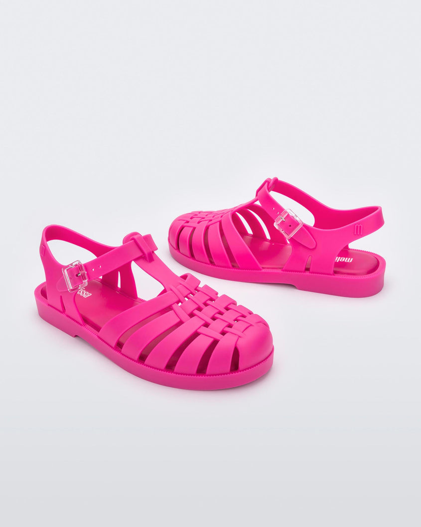 Angled view of a pair of pink Melissa Possession sandals with a closed toe front weft design connected to a top strap with a buckle.