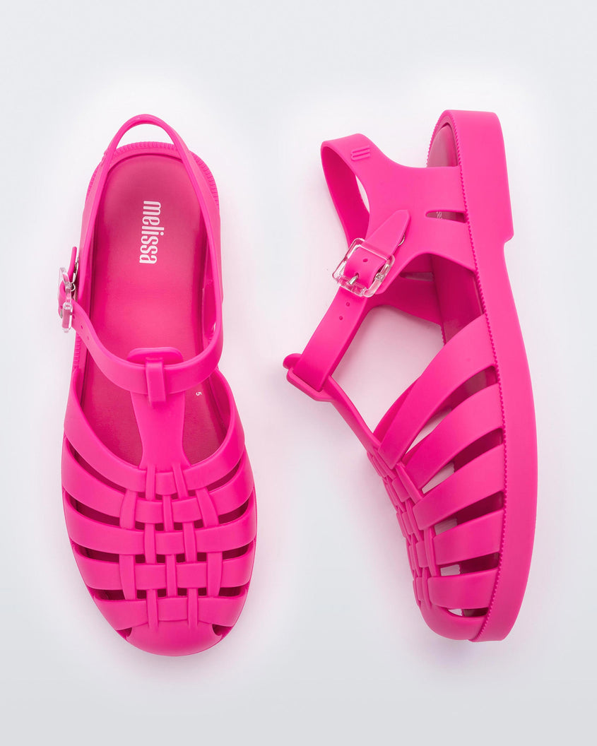 Top and side view of a pair of pink Melissa Possession sandals with a closed toe front weft design connected to a top strap with a buckle.