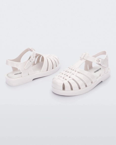 An angled front and back view of a pair of white Mini Melissa Possession sandals with several straps and a white base.