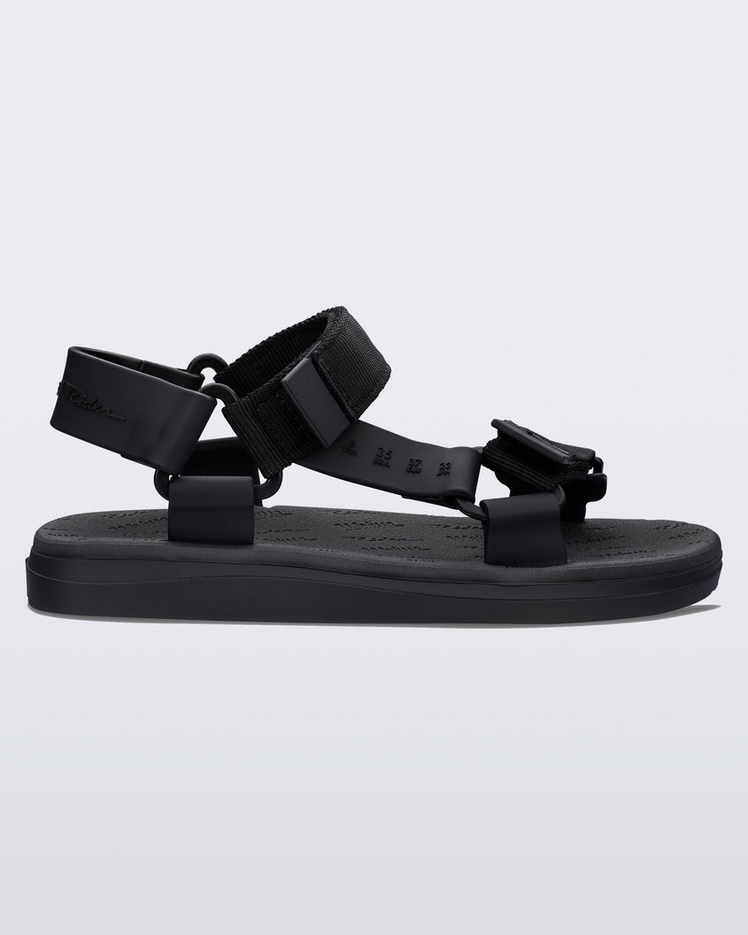 Side view of a black Mini Melissa Papete sandal with black straps.
