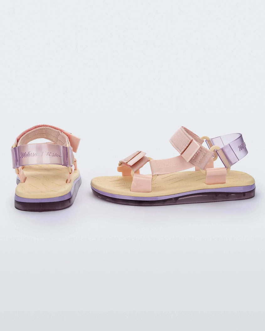 Side and back view of a pair of yellow soled Melissa Papete sandals with pink and transparent purple straps.
