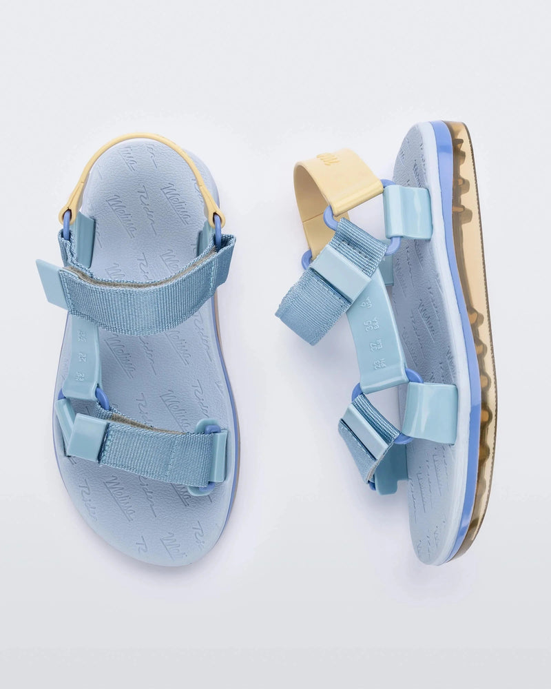 Side and top view of a pair of blue Melissa Papete sandals with blue and beige straps.