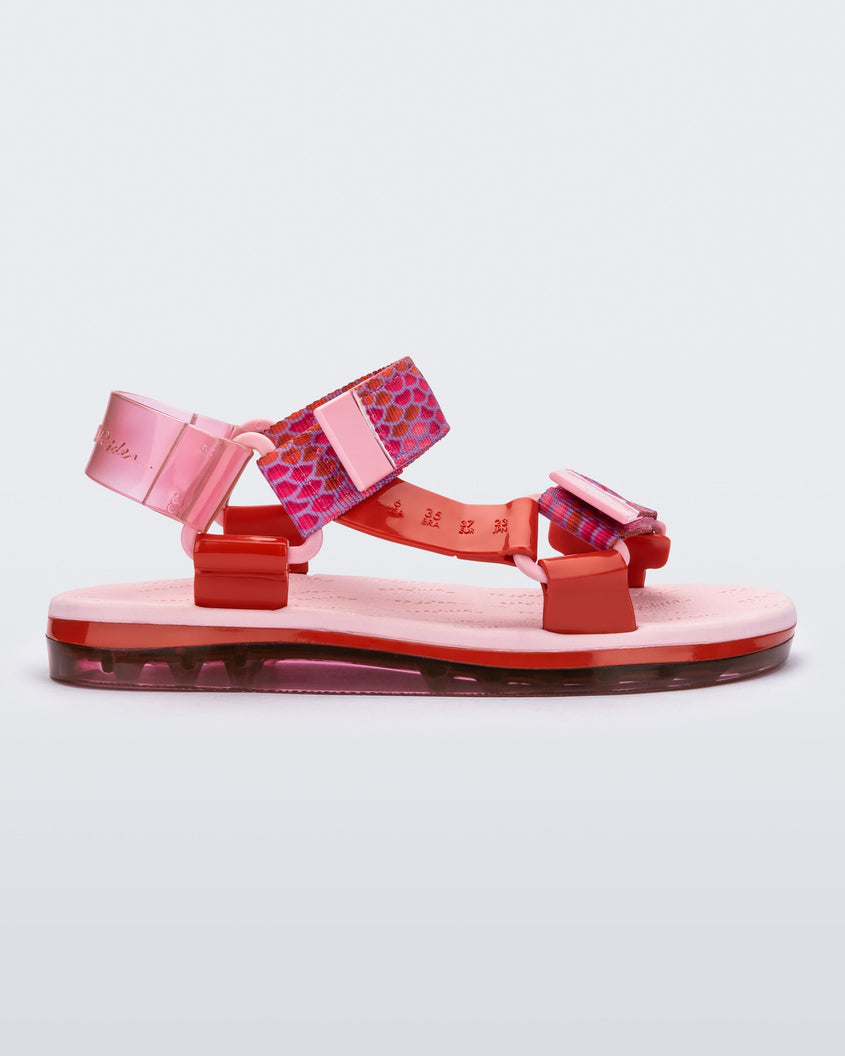 Side view of a pair of pink Melissa Papete sandals with patterned pink, red, and transparent pink straps.