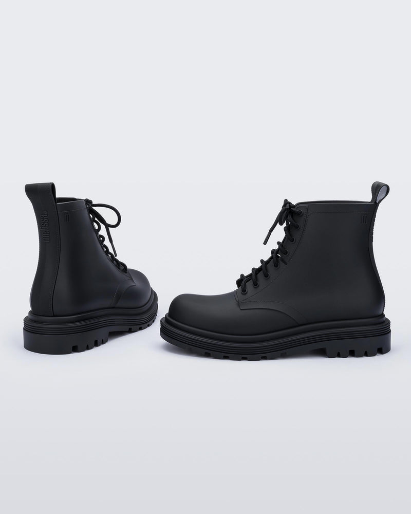 An angled back and side view of a pair of matte black Melissa Coturno boots with a black base, laces and sole.