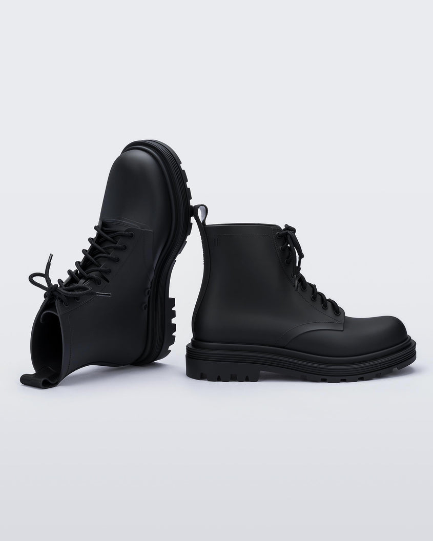 An angled top and side view of a pair of matte black Melissa Coturno boots with a black base, laces and sole.