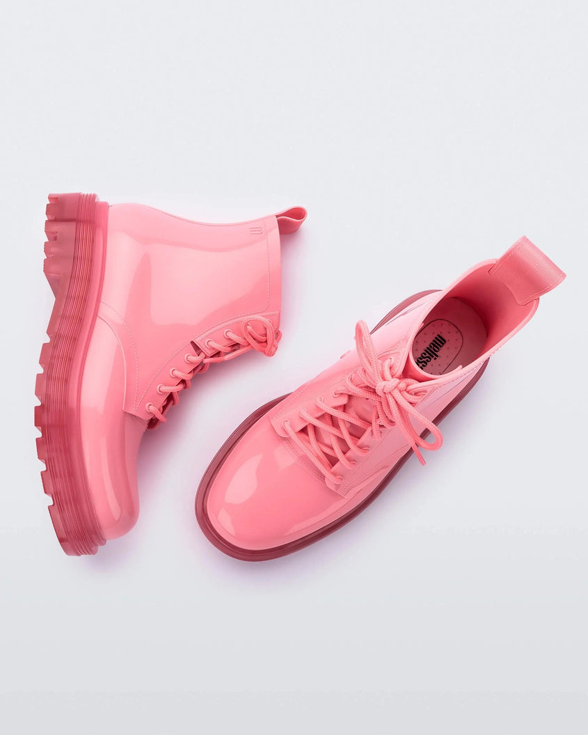 A top and side view of a pair of clear pink/pink Melissa Coturno boots with a pink base, laces and sole.