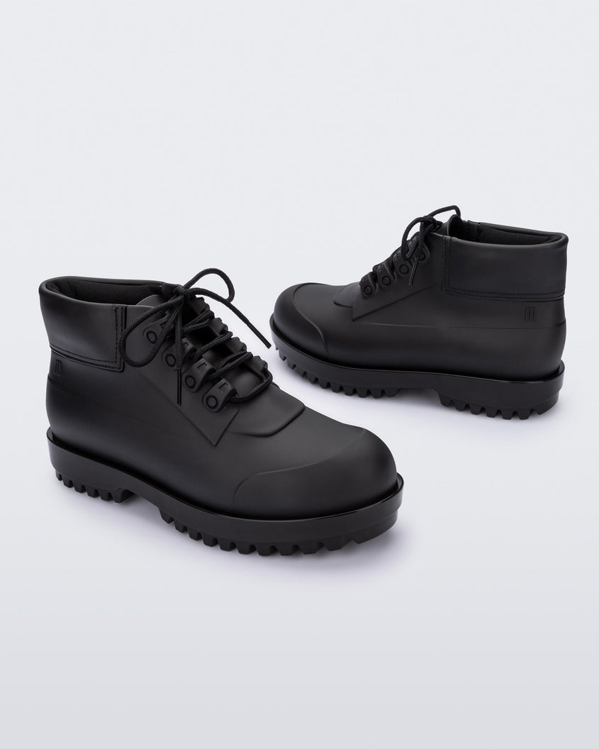 An inner and outter side view of a pair of matte black Melissa Ares combat boots with a black base, laces and tractor sole.