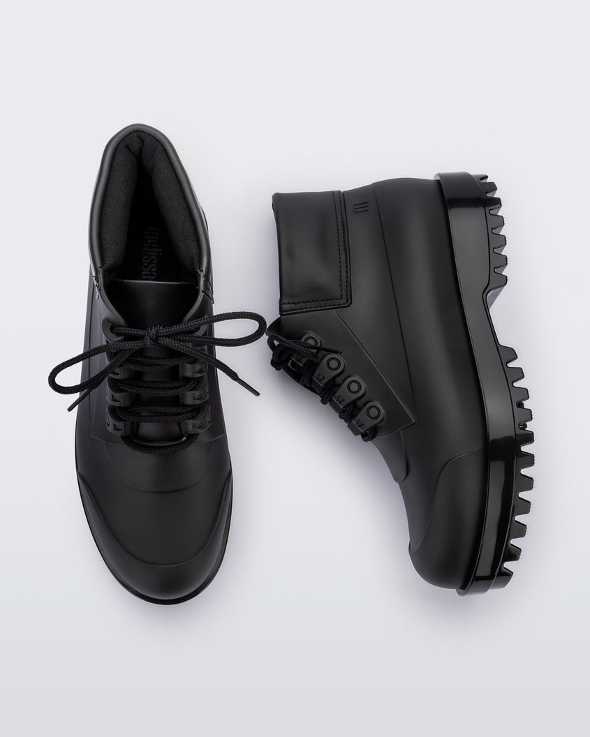 A top and side view of a pair of matte black Melissa Ares combat boots with a black base, laces and tractor sole.