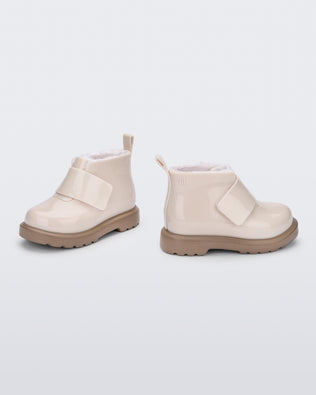 Angled and side view of a pair of beige/brown baby Chelsea boots with faux fur lining