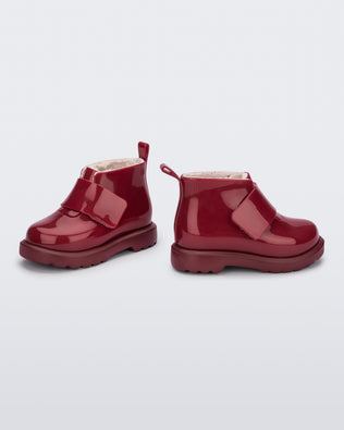 Angled and side view of a pair of red baby Chelsea boots with faux fur lining