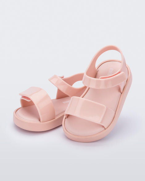 An angled front and side view of a pair of pink Mini Melissa Jump sandals with velcro straps.