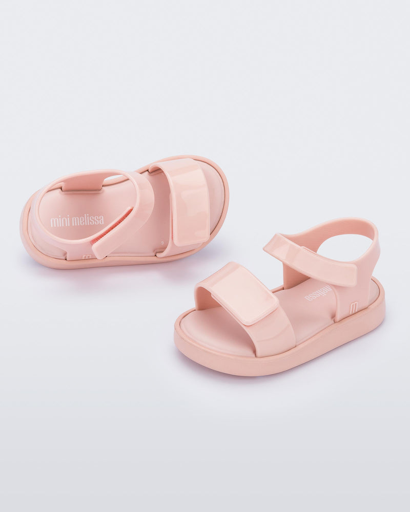 Top and angled view of a pair of pink Mini Melissa Jump sandals with velcro straps.