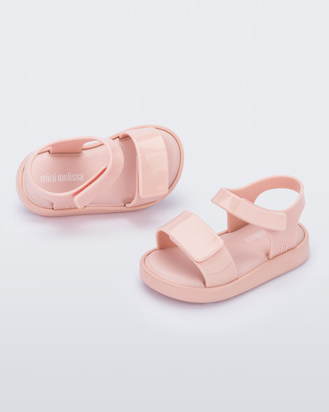 Top and angled view of a pair of pink Mini Melissa Jump sandals with velcro straps.