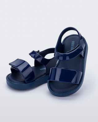 An angled side and top view of a pair of blue Mini Melissa Jump sandals with velcro straps.