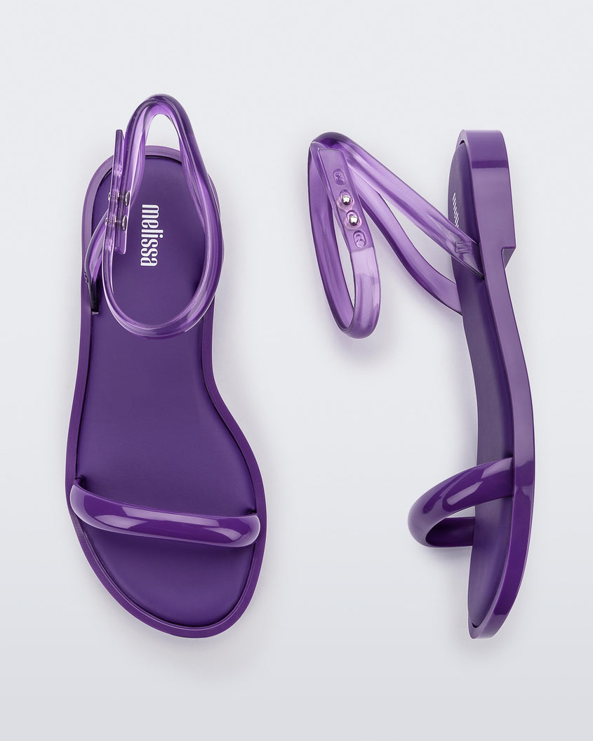 A side and top view of a pair of purple Melissa Wave Sandals with a purple front strap and clear purple ankle strap.
