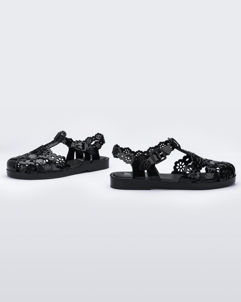 Angled view of a pair of Melissa Possession fisherman sandals in black with cut out lace detail on the straps.