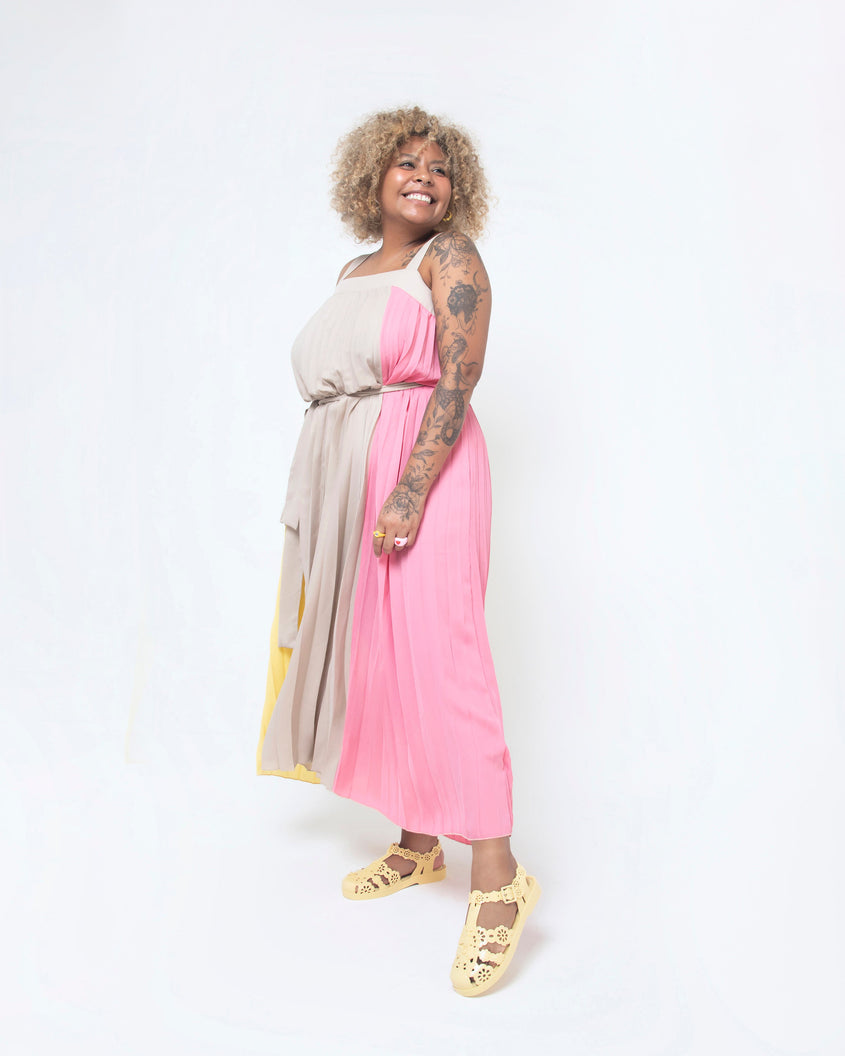 Model posing in a pink and natural colored dress wearing a pair of Melissa Possession fisherman sandals in yellow with cut out lace detail on the straps.