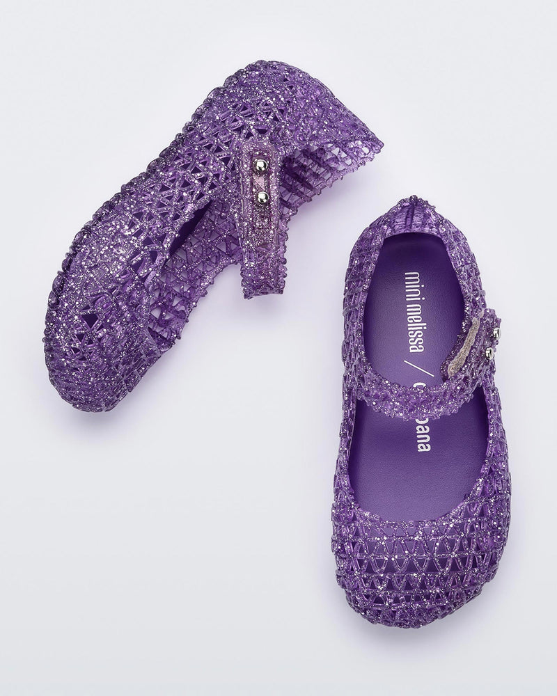 Top and angled view of a pair of Mini Melissa Campana flats for baby in purple glitter with an open woven texture.