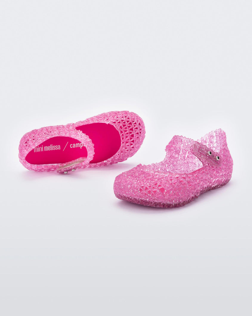 Top and angled view of a pair of Mini Melissa Campana flats for baby in pink glitter with an open woven texture.