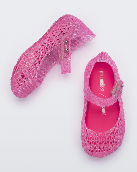 Top and angled view of a pair of Mini Melissa Campana flats for baby in pink glitter with an open woven texture.
