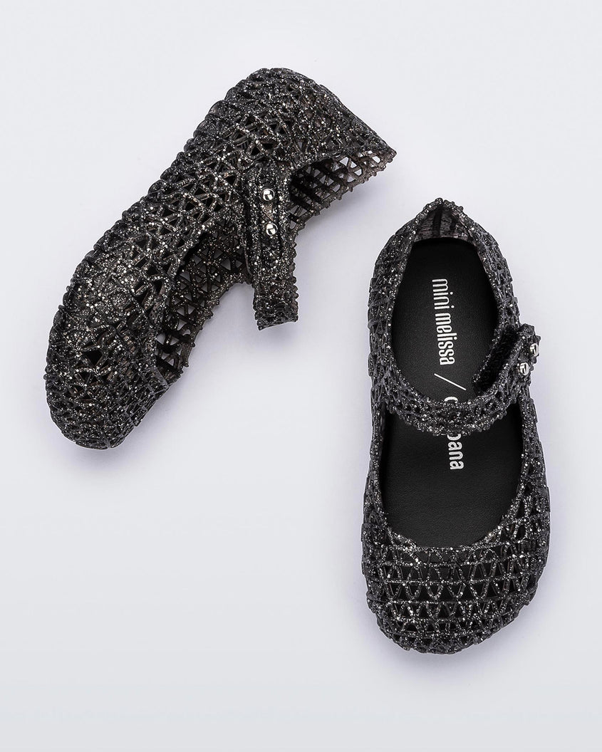 Top and angled view of a pair of Mini Melissa Campana black glitter flats for baby with an open woven texture.