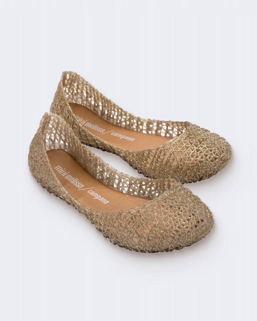 An angled front view of a pair of gold glitter Mini Melissa Campana flats with a woven detail base.