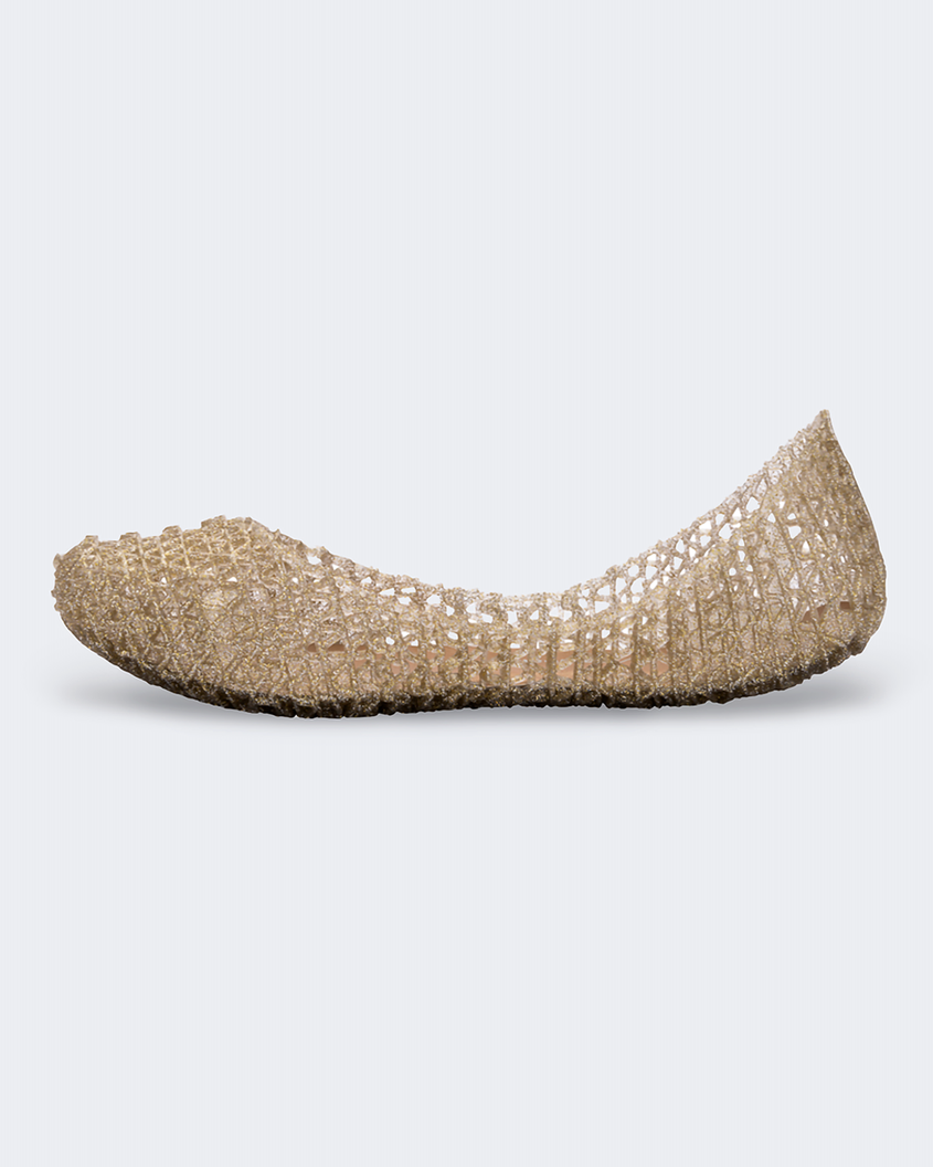 An inner side view of a gold glitter Mini Melissa Campana flat with a woven detail base.