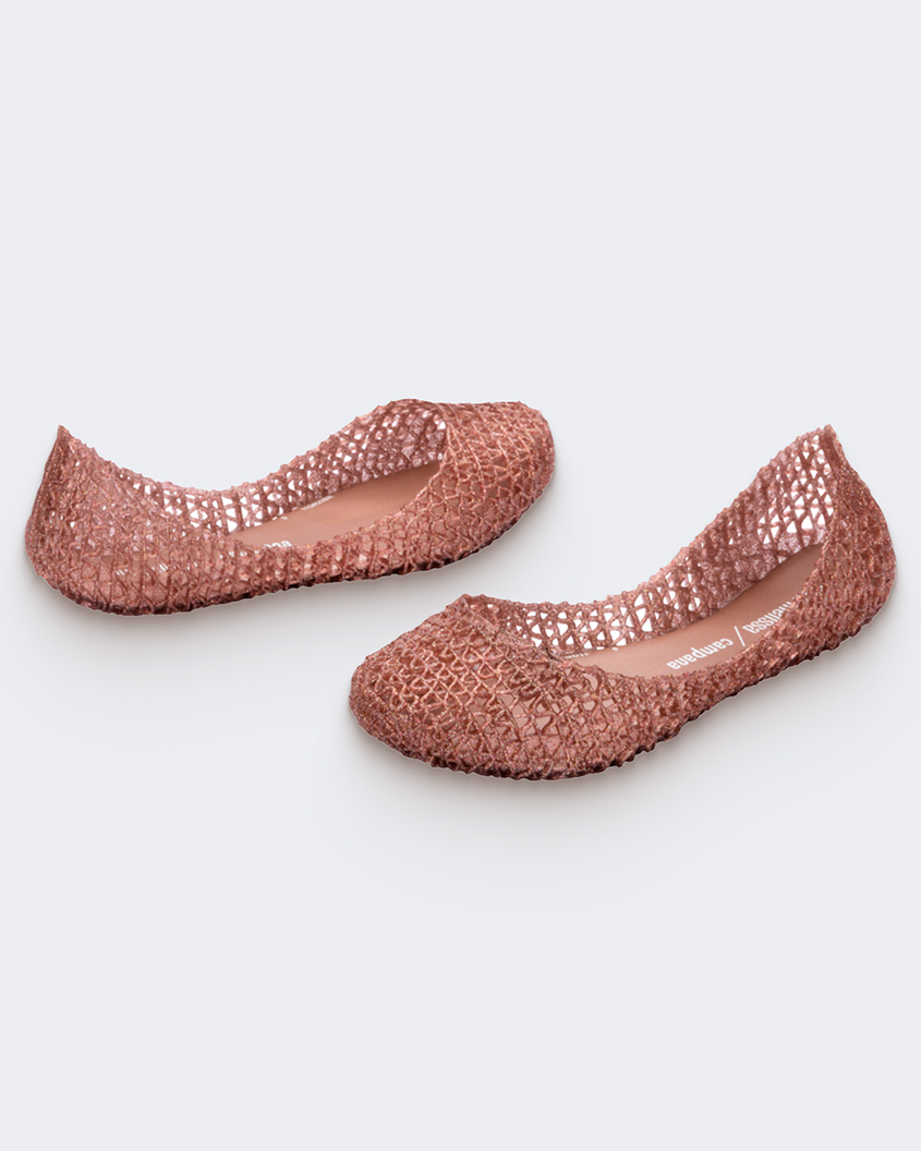 An angled side view of a pair of rose glitter Mini Melissa Campana flats with a woven detail base.